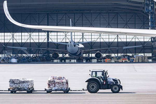 Cargo tractor driving past airplane hanger